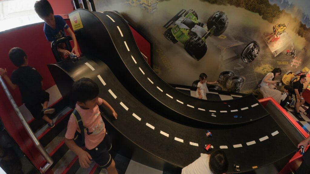 黒い坂道コースの上から子どもたちがレゴの車を走らせる様子