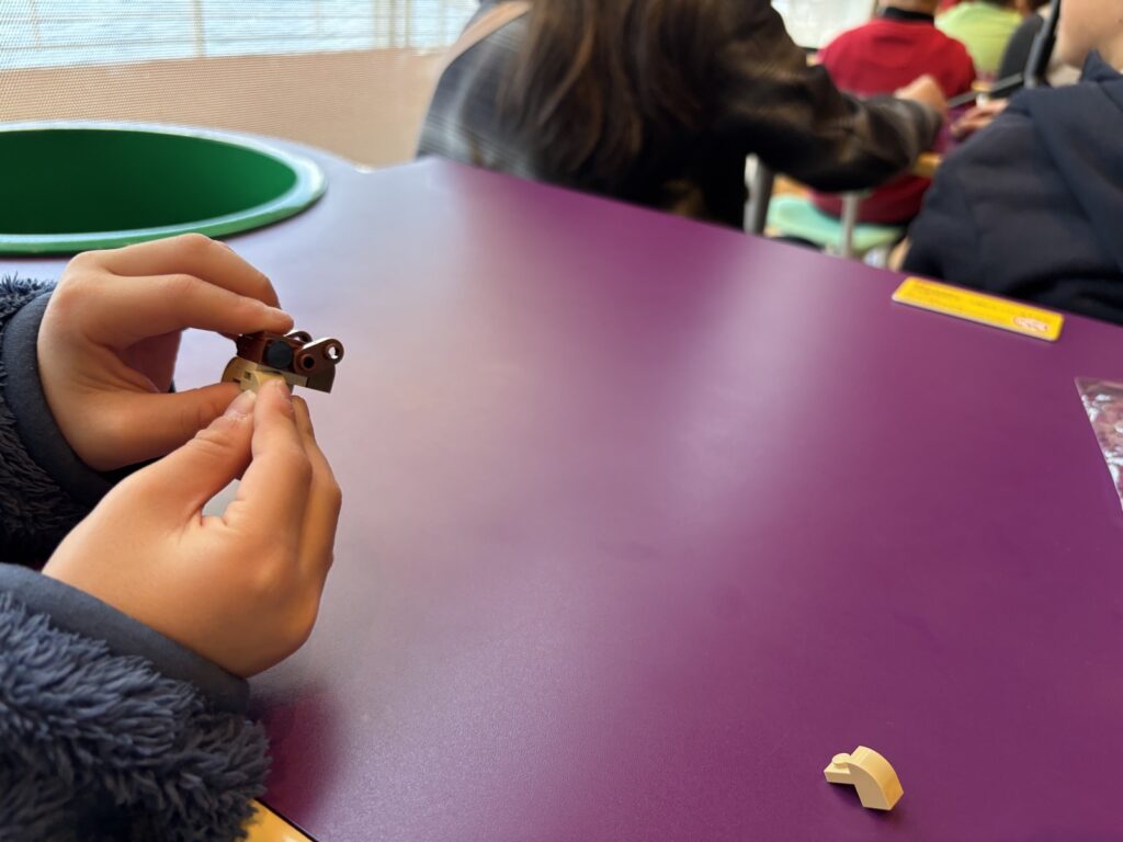 レゴ教室の机で小さな茶色のパーツを組み合わせる子どもの手元