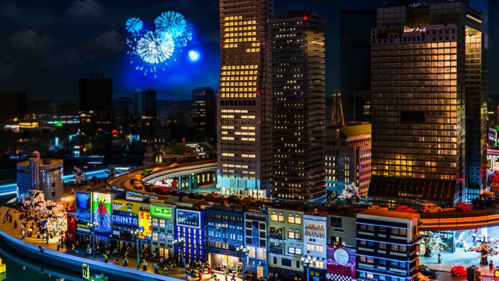 夜の演出で窓に明かりがともり、花火が上がるミニランドの大阪の街